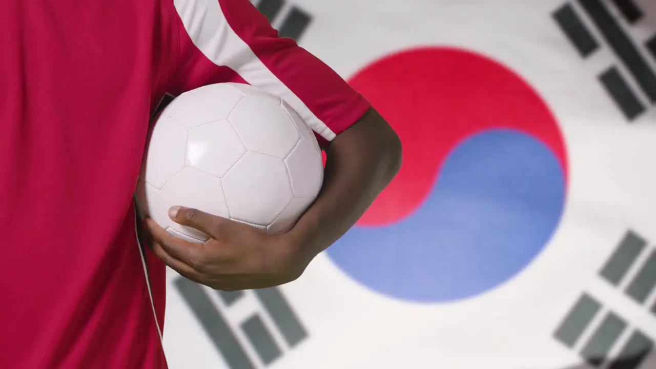 Young Footballer Walking Holding Football In Front of South Korea Flag