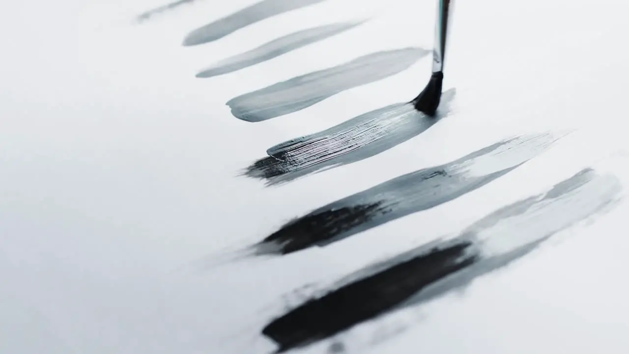 Close up of brush painting stripes with black paint on white background slow motion