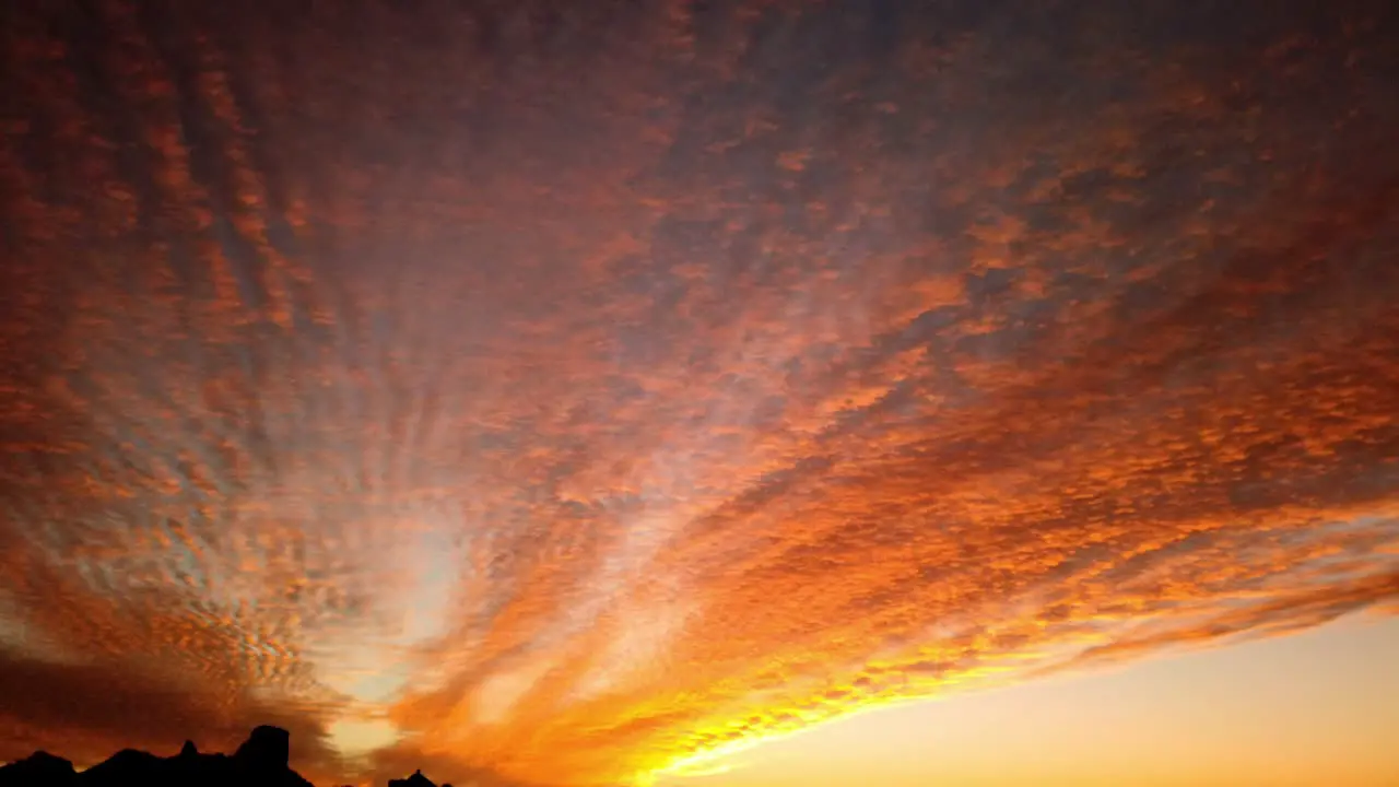 Motion time lapse video of richly colored and textured clouds near a setting sun in the Arizona desert