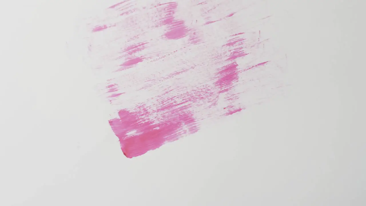 Close up of pink paint shapes on white background with copy space slow motion