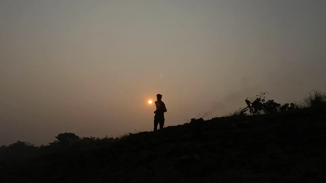 Silhouette of fast jogger running in slow motion at evening sky rural landscape