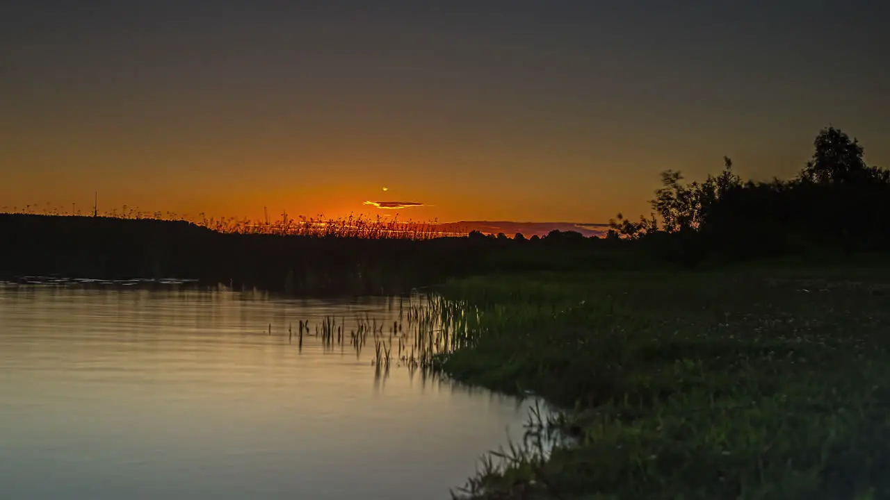 Golden sunrise over a lake with the glowing sun reflecting off the water low angle time lapse