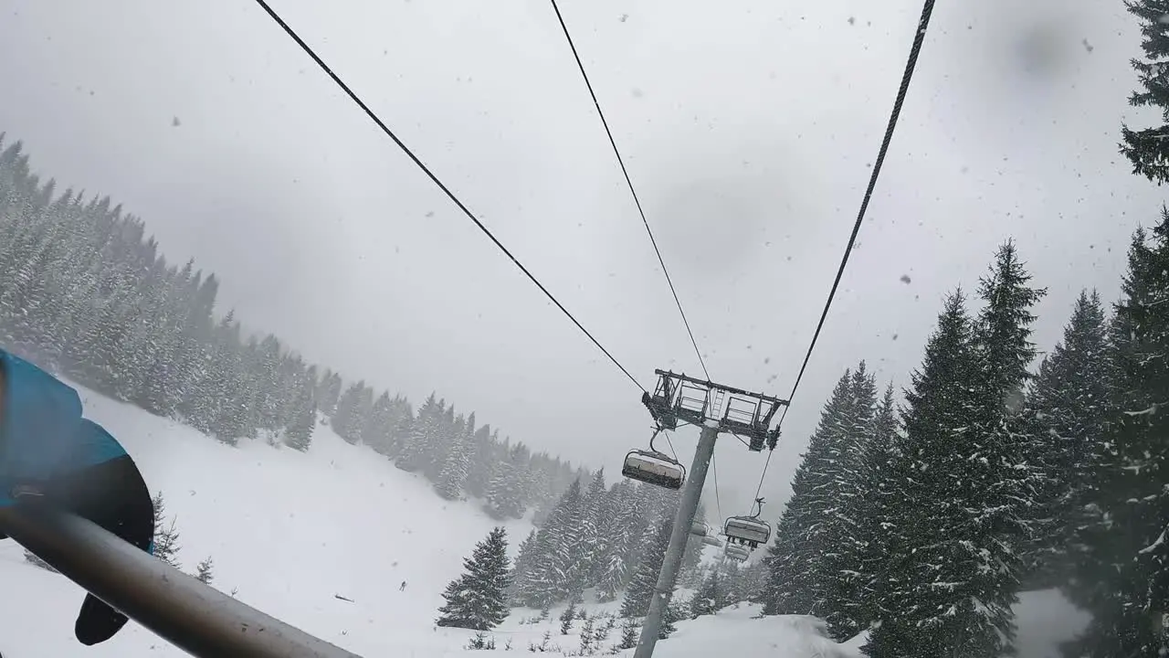 POV Shot Of Skier On Chair Lift Across Snow Covered Mountain And Trees 2