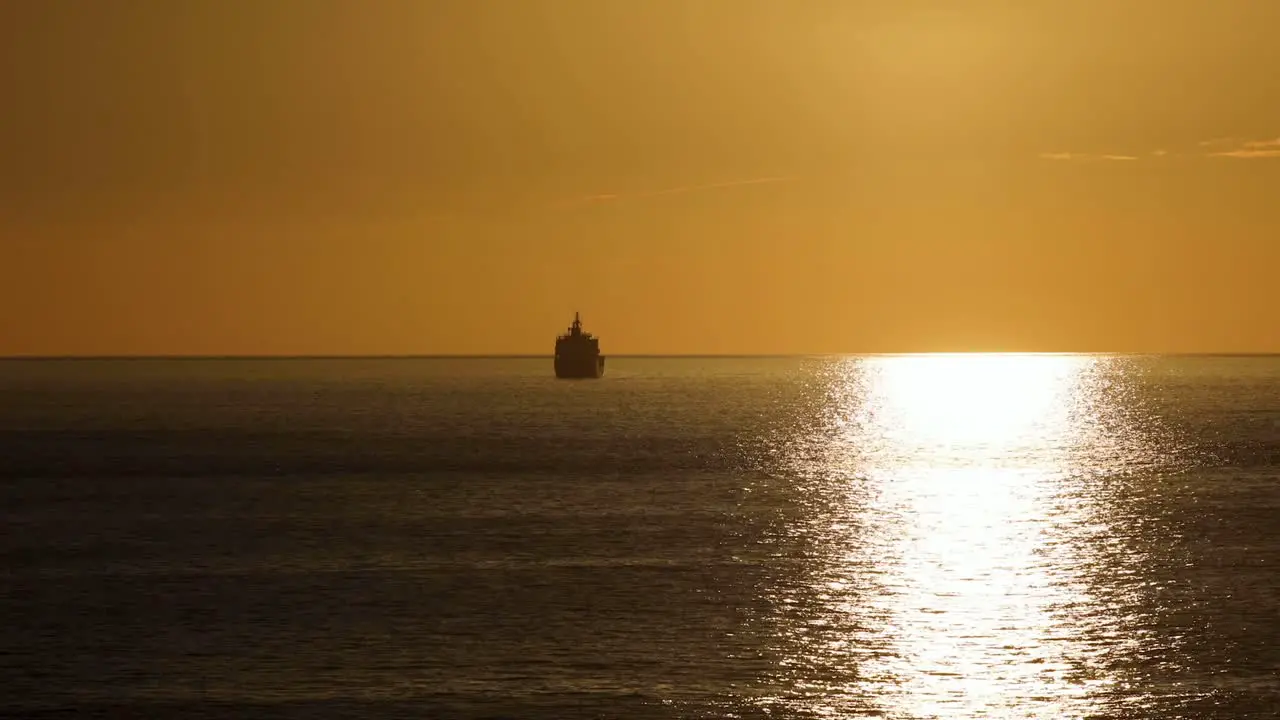 From Behind clean Land A Boat Moves Across The Ocean During Majestic Sunset