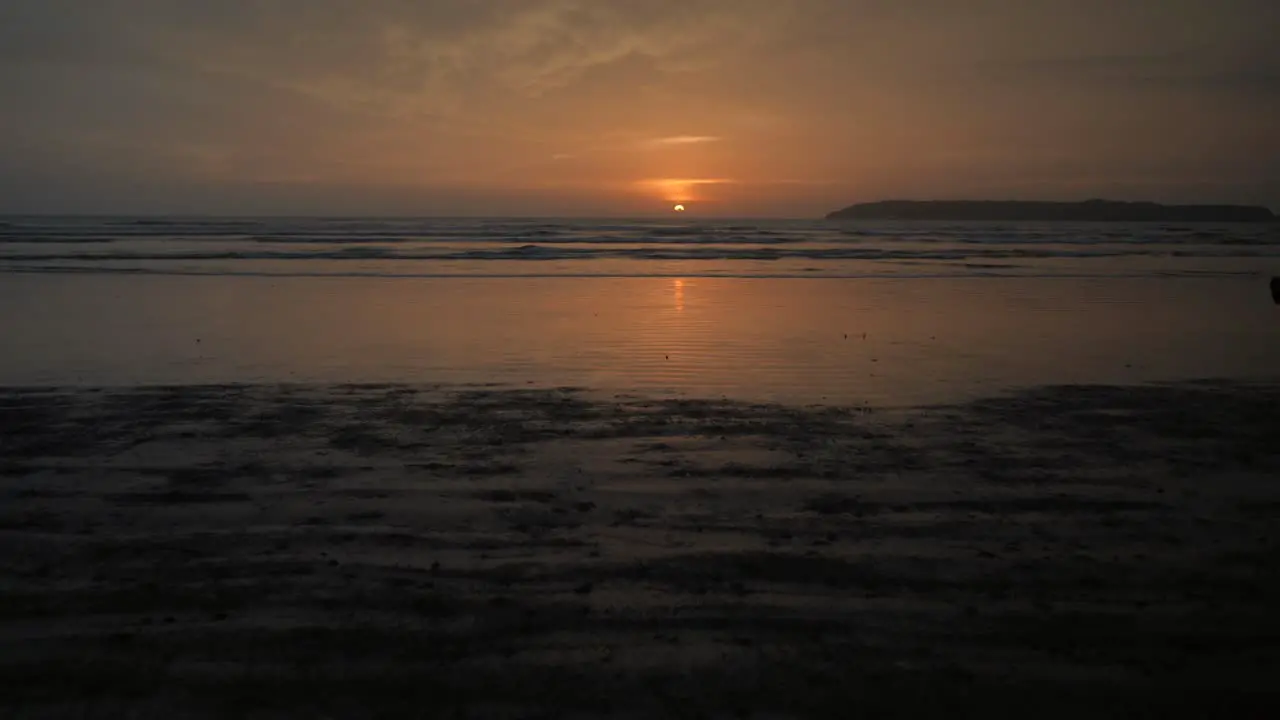 Landscape view of a young woman silhouette running on a sandy beach by the ocean at sunrise