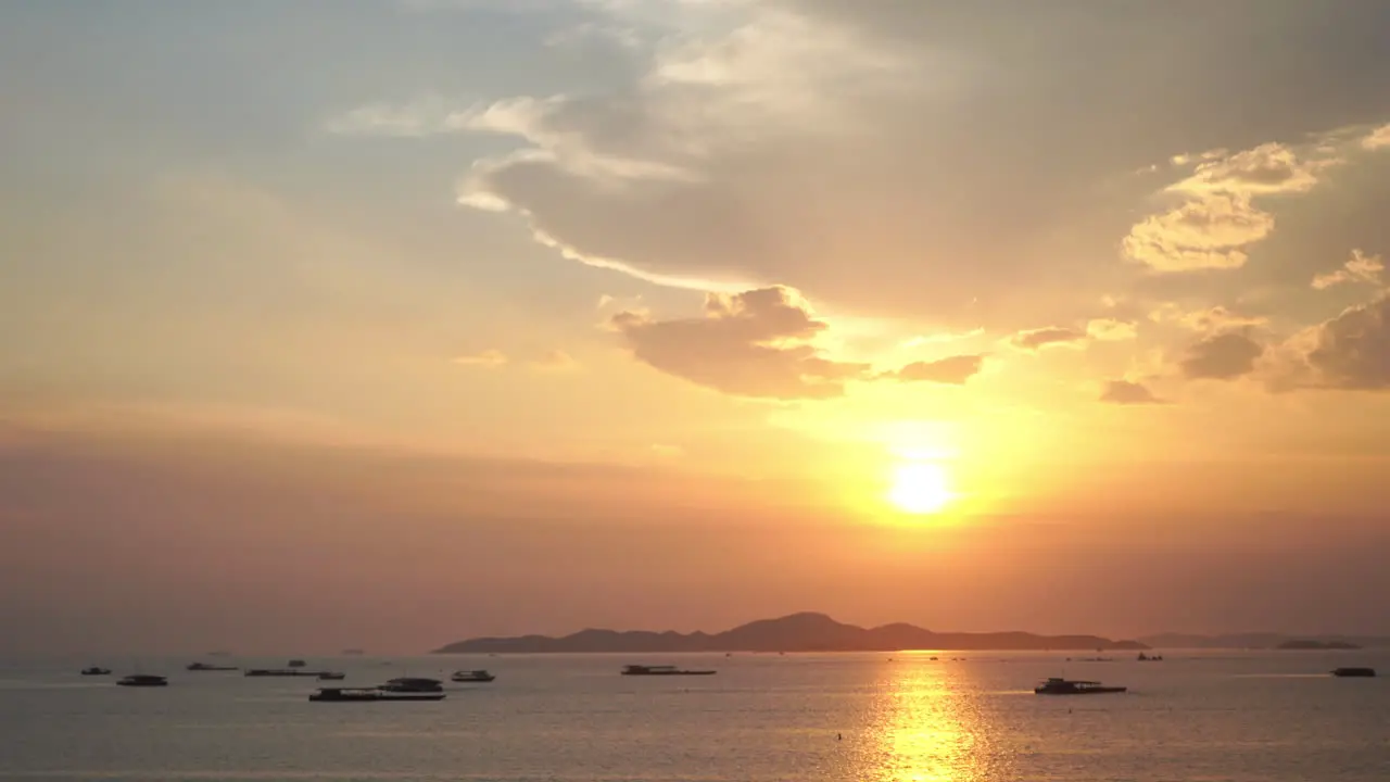 Stunning tropical sunset behind distant island and boats anchored in calm ocean