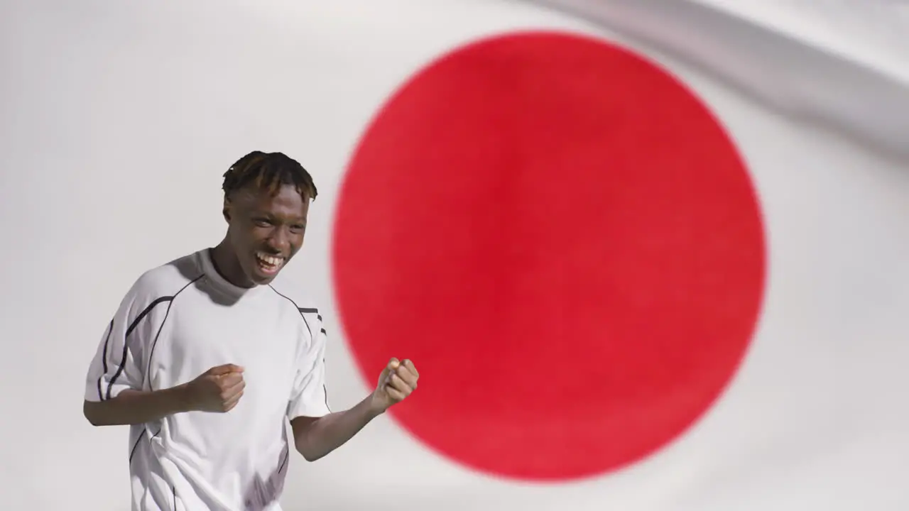 Young Footballer Celebrating to Camera In Front of Japan Flag 