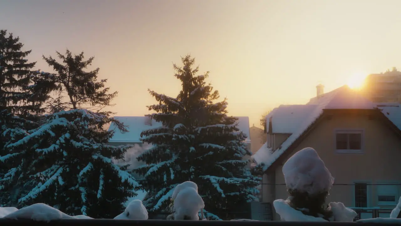 Cinematic Timelapse of a Sunrise during a cold snowy winter with Houses with Chimney Smoke and Trees in the background