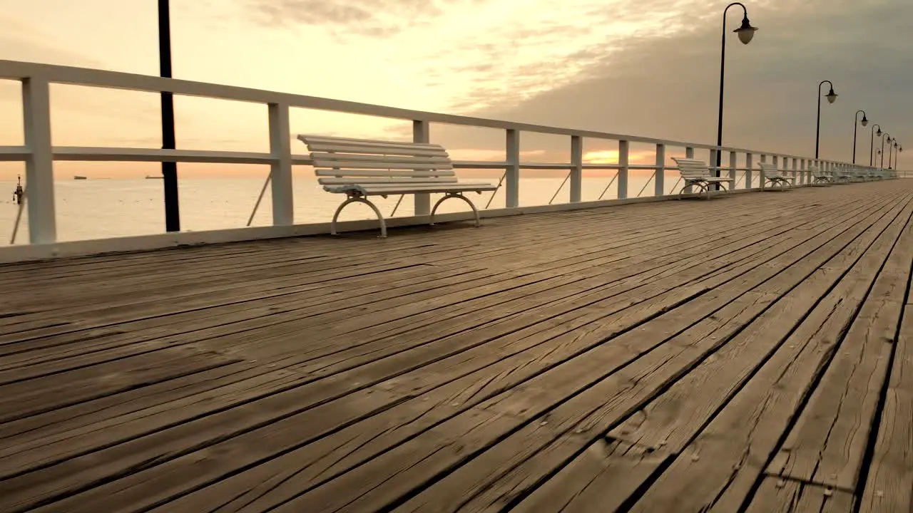 Aerial footage boards and benches on the pier at sunrise at the seaside