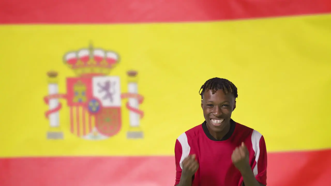 Young Footballer Celebrating to Camera In Front of Spain Flag 