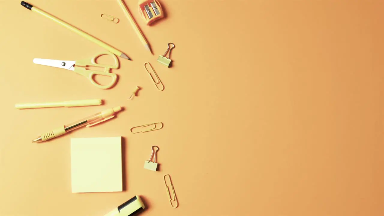 Overhead view of school stationery with copy space on orange background in slow motion