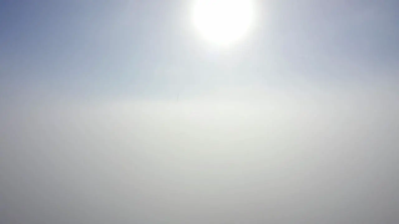 Bright Sun In Blue Sky With Wind Turbines In Clouds