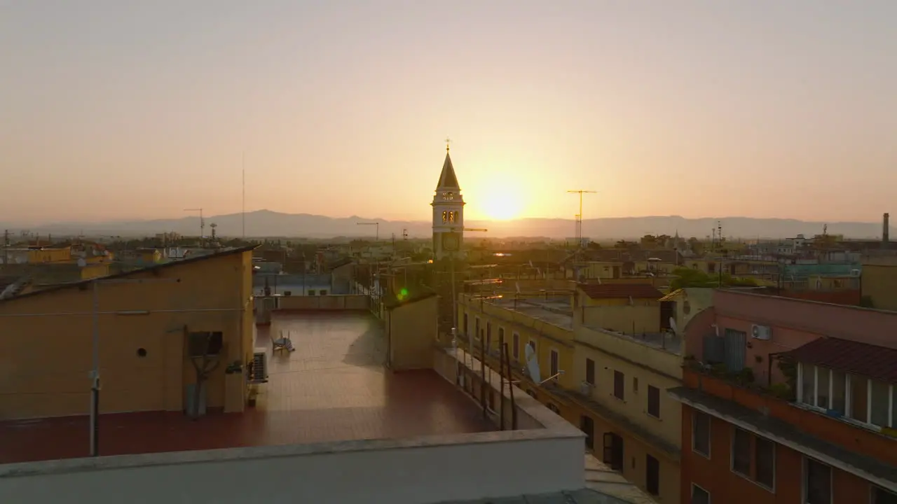 Slide and pan footage of tower protruding above other buildings in city Aerial morning shot against rising sun Rome Italy