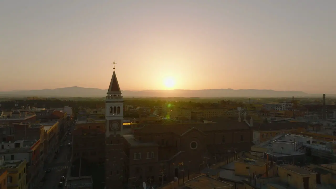 Aerial view of church and square tower against sunrise sky Backwards reveal of buildings in city centre Rome Italy