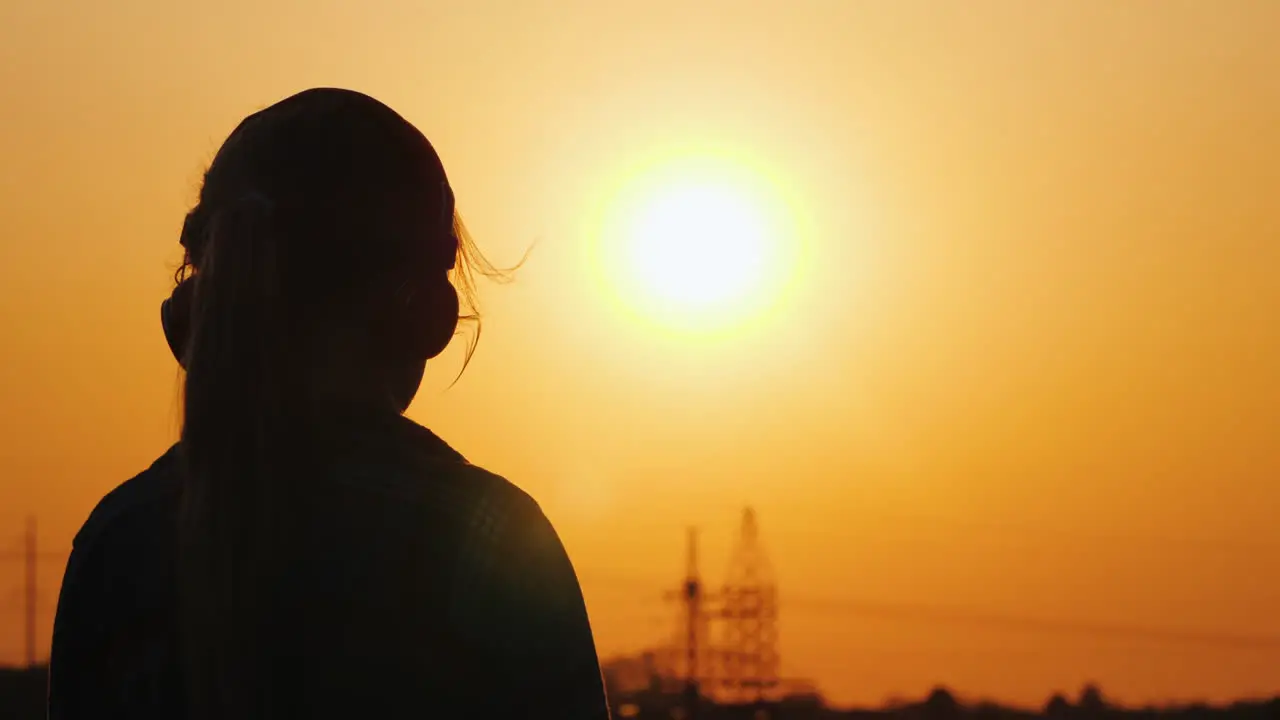 Silhouette Of A Girl In Headphones Listening To Music Against The Backdrop Of A Large Setting Sun An