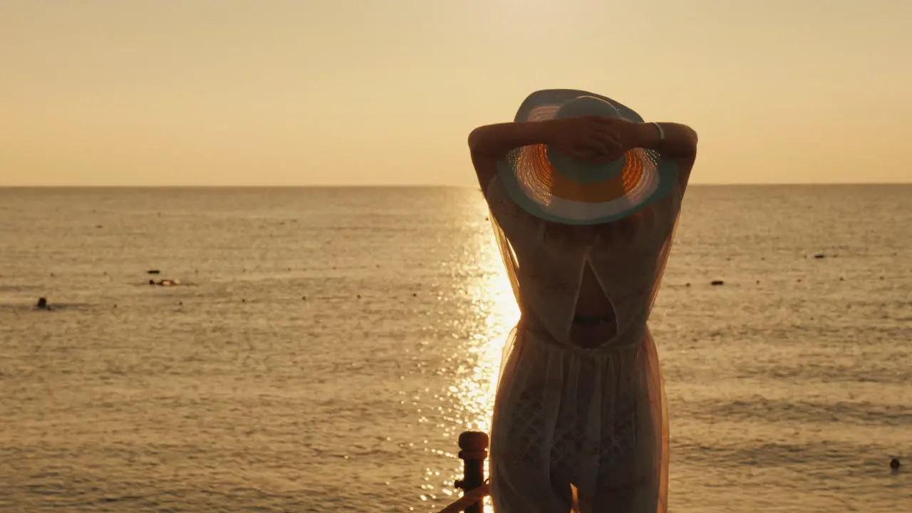 A Young Woman In A Light Dress And Hat Meets The Dawn At The Sea A Ship Is Visible In The Distance D