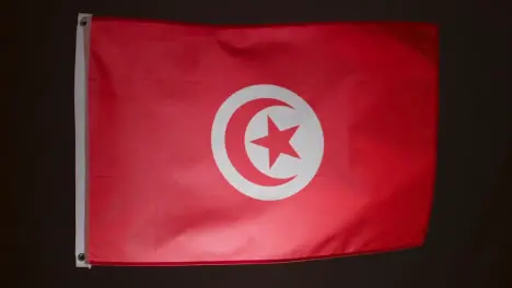 Studio Shot Of Flag Of Tunisia Flying Against Black Background