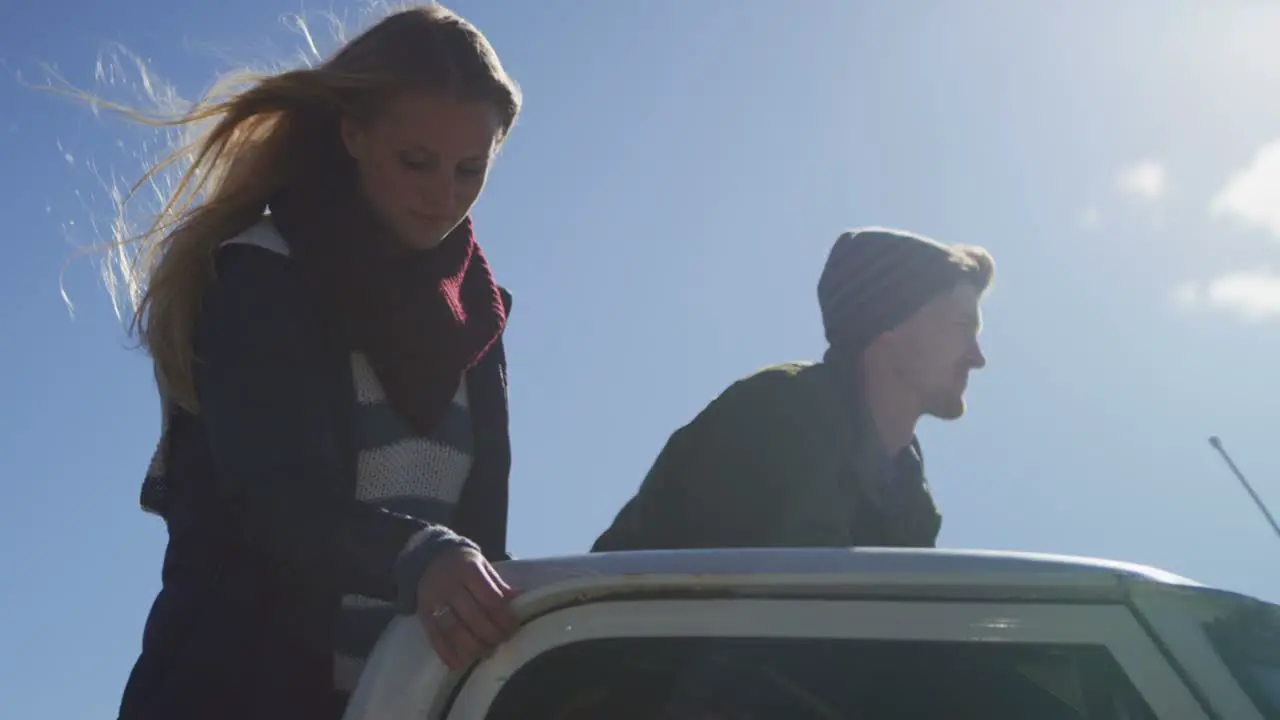 A couple stands in the bed of a pickup truck as it drives along a rural road 1