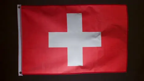 Studio Shot Of Flag Of Switzerland Flying Against Black Background