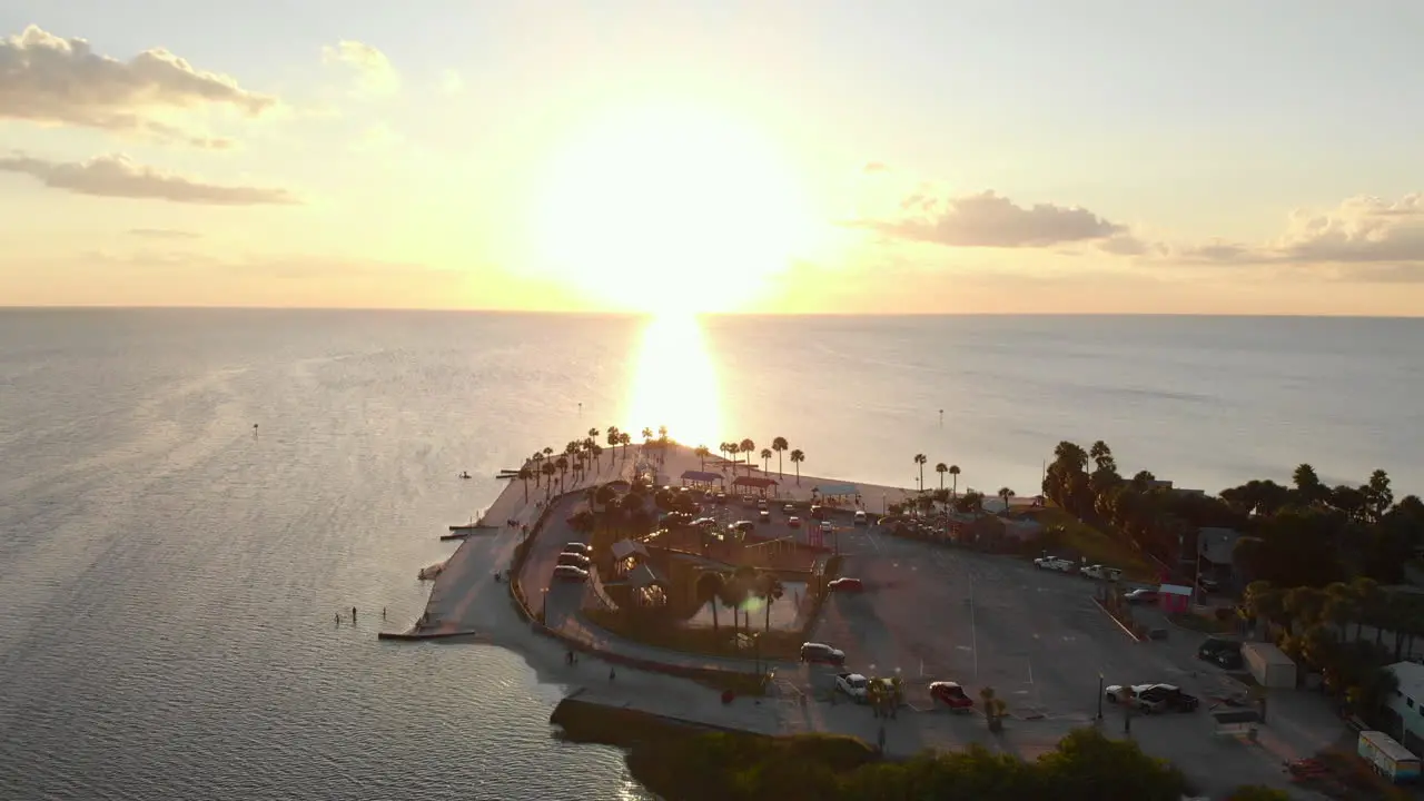 Aerial pullback immaculate white beach with sunrise over water