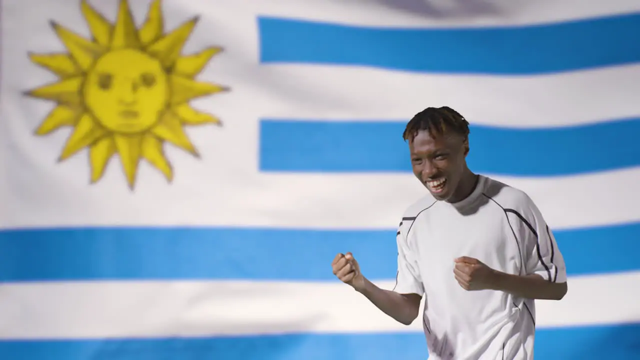 Young Footballer Celebrating to Camera In Front of Uruguay Flag 01