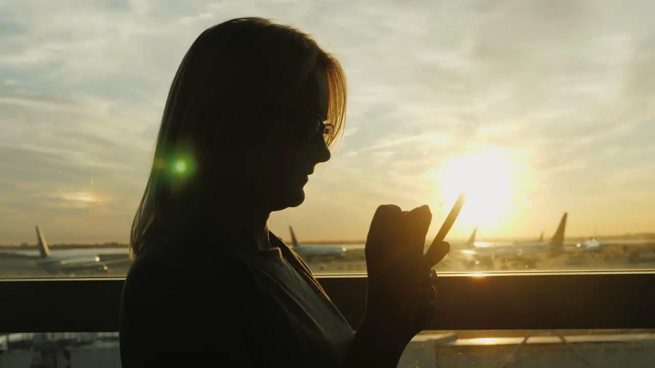 Woman Using Smartphone In Airport At Sunset