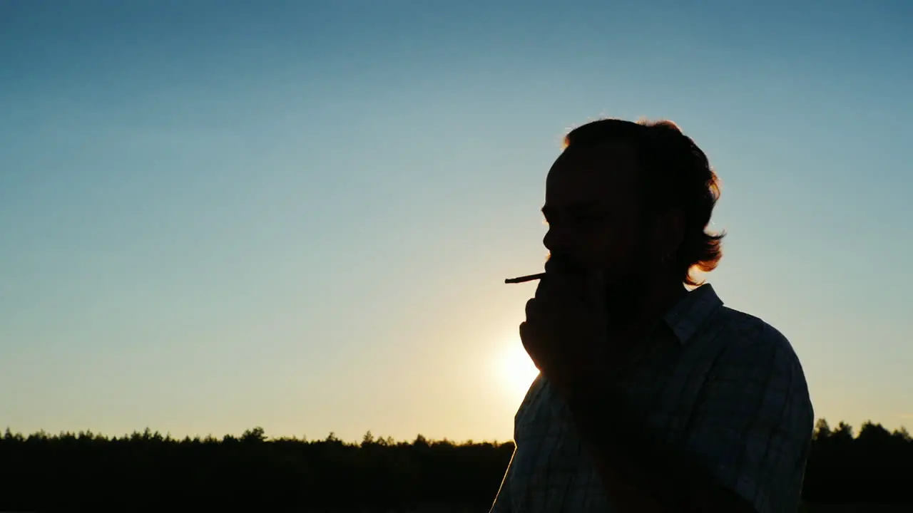 Silhouette Of A Bearded Man Who Smokes At Sunset