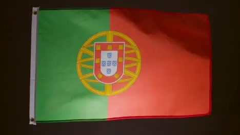 Studio Shot Of Flag Of Portugal Flying Against Black Background