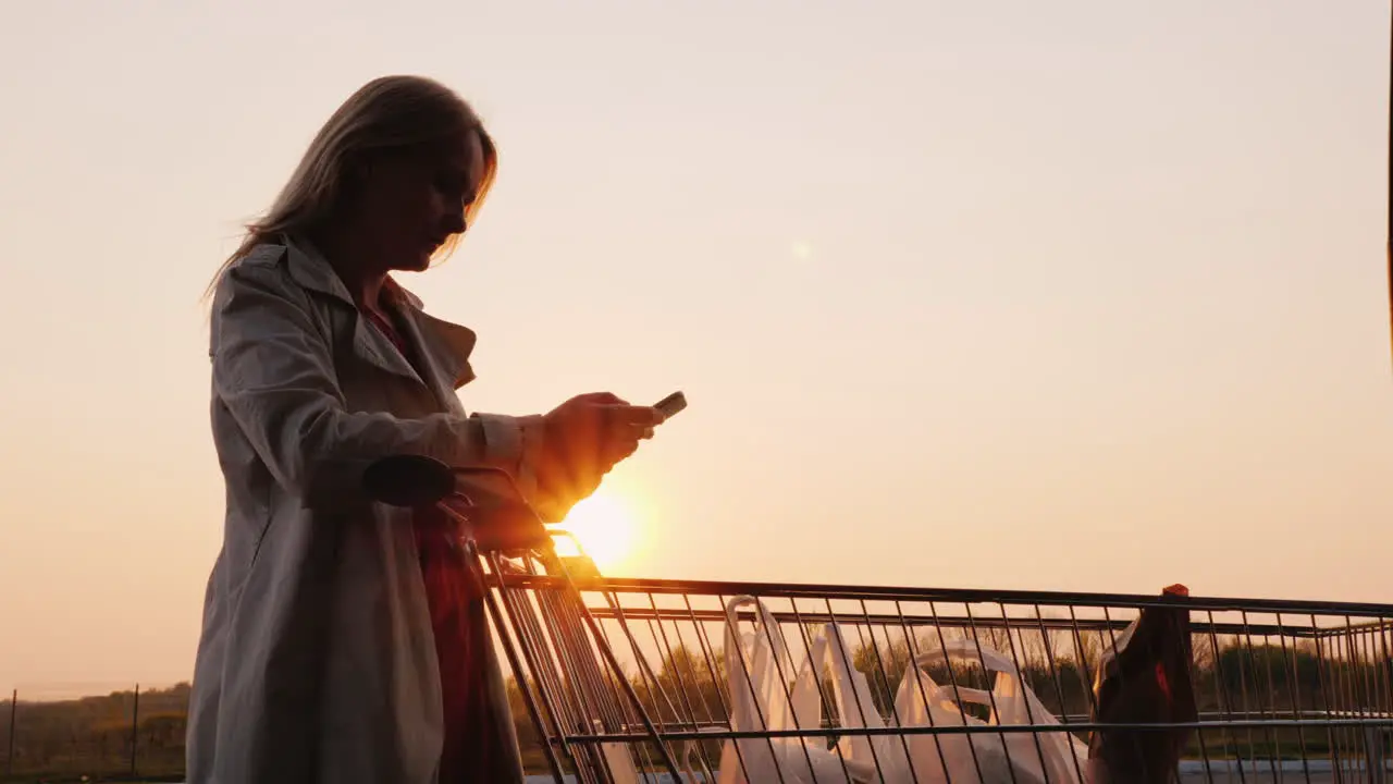 Woman Check Their Purchases In The Trolley With A List On The Smartphone