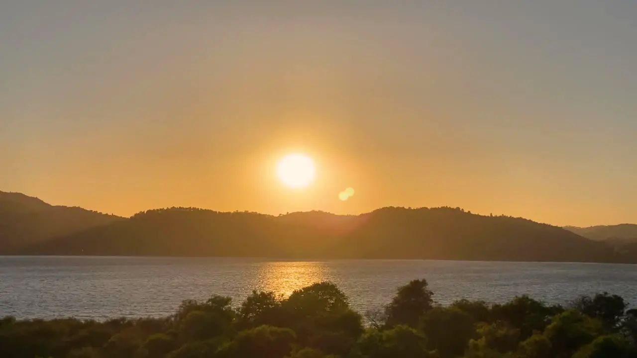 Beautiful and romantic seaside sunset Cinemagraph with some wind moving gently at the atlantic coast of Portugal and the sun disappearing behind a mountain