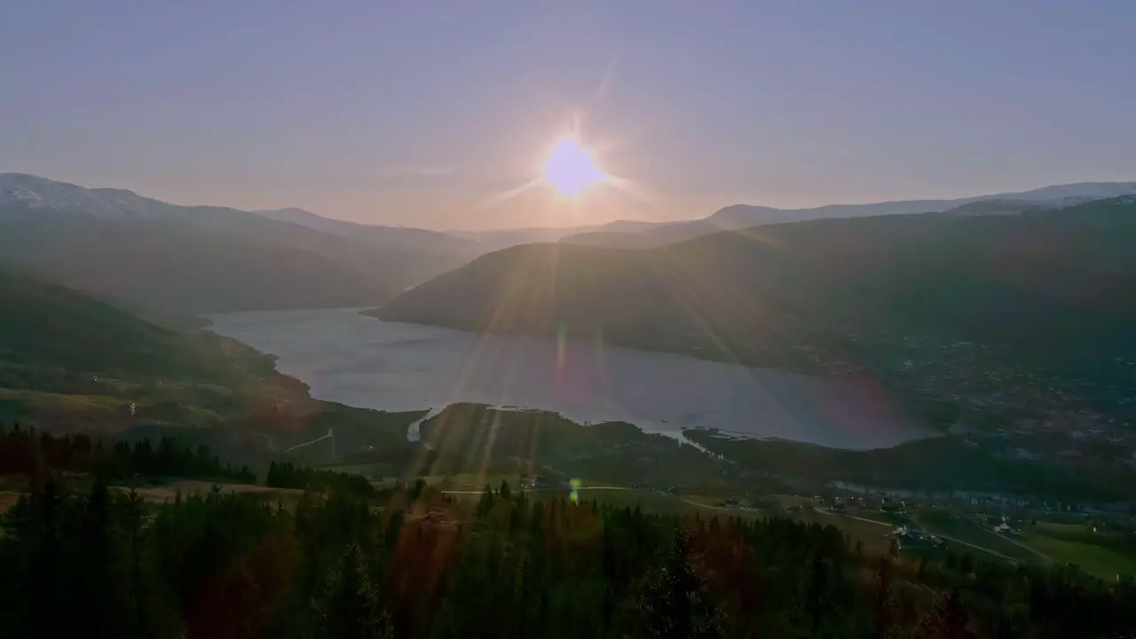 High angle shot over town along the slope of a mountain with river flowing through the range in Norway on a brighht sunny day