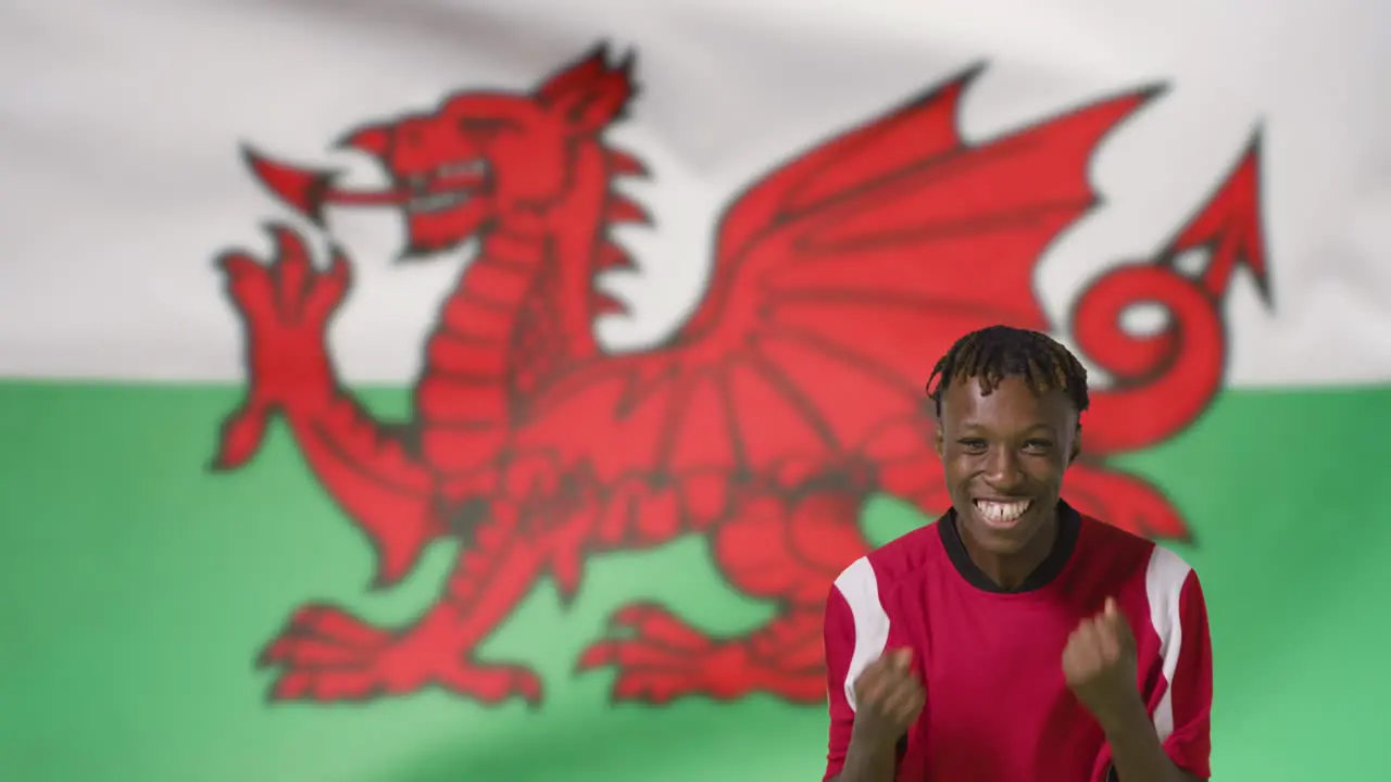 Young Footballer Celebrating to Camera In Front of Wales Flag 01