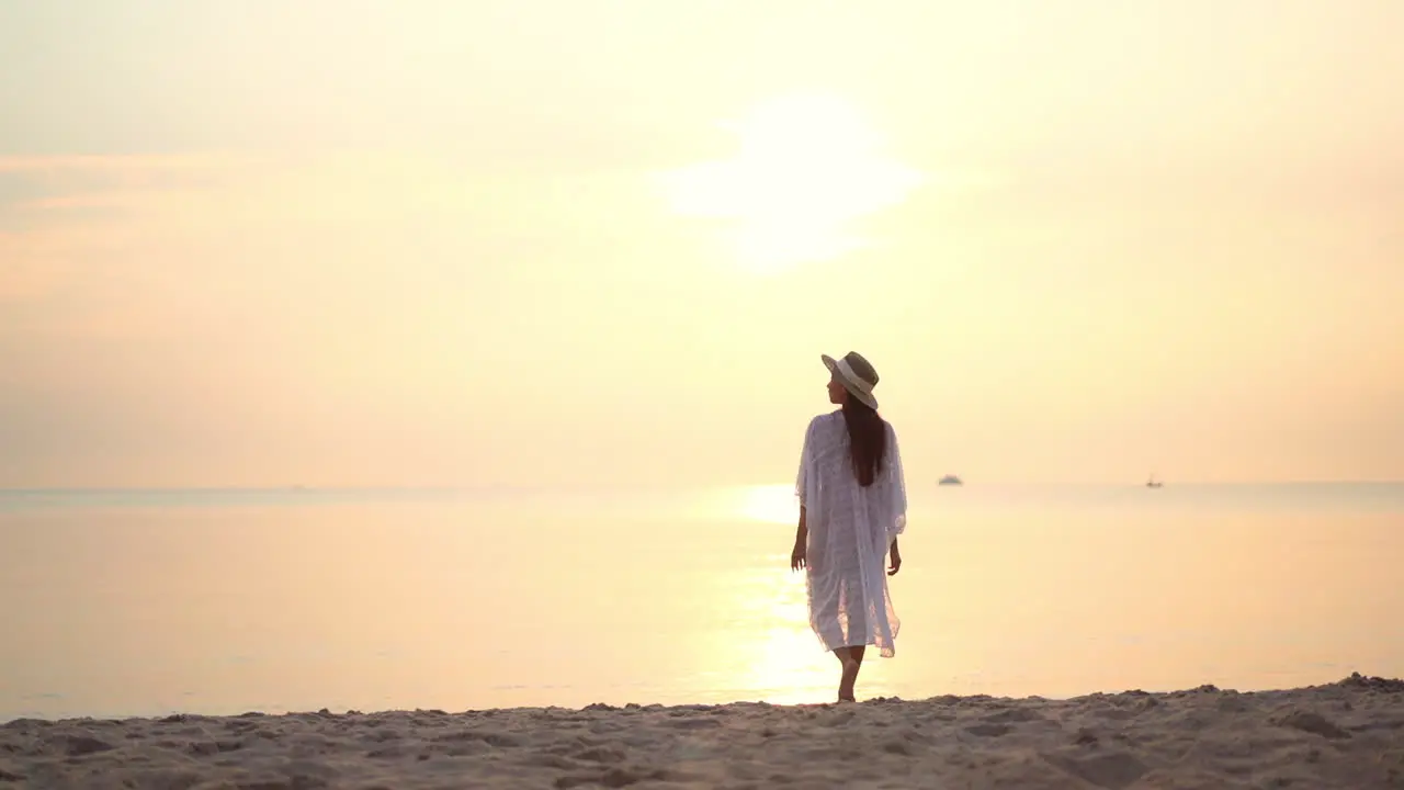 Beautiful woman walks on beach and raises arms