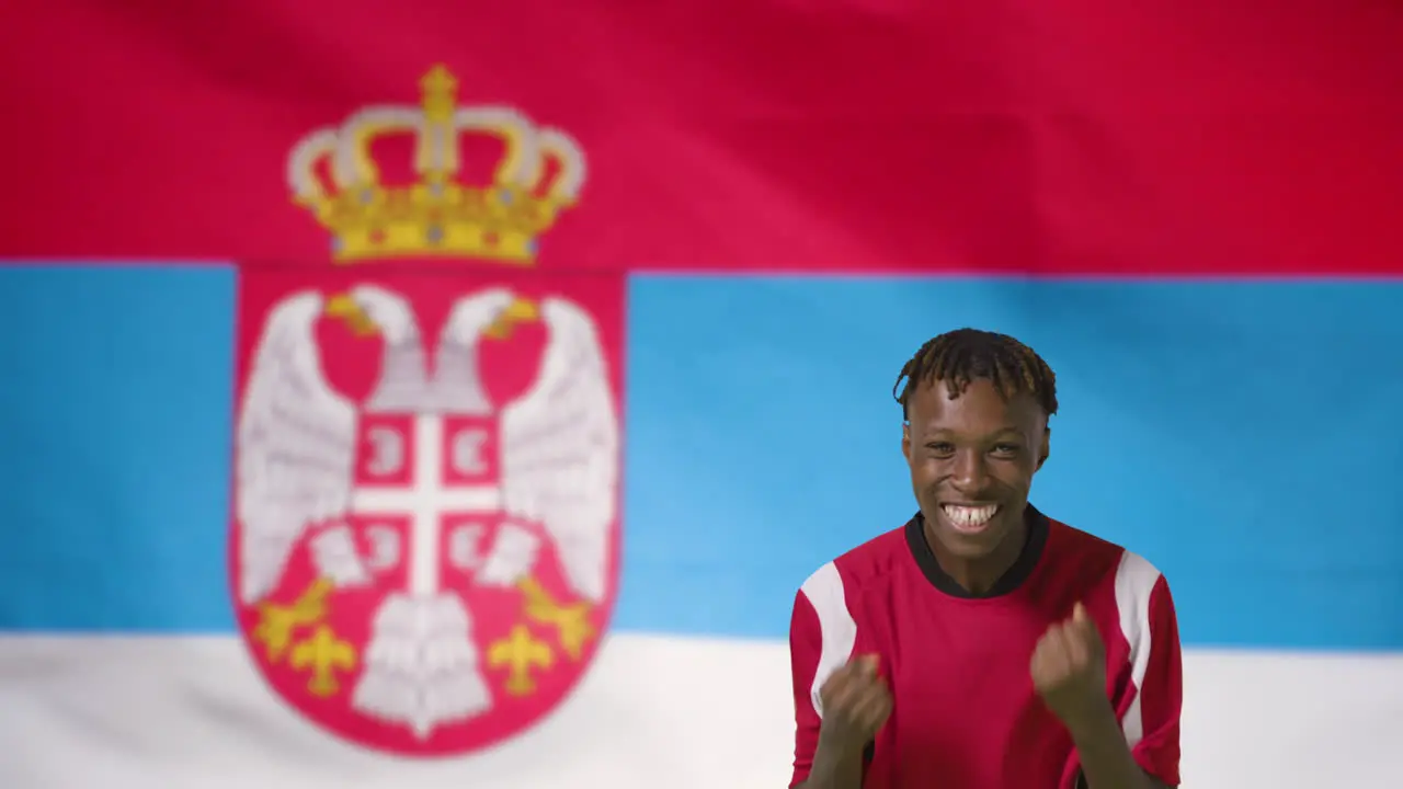 Young Footballer Celebrating to Camera In Front of Serbia Flag 01