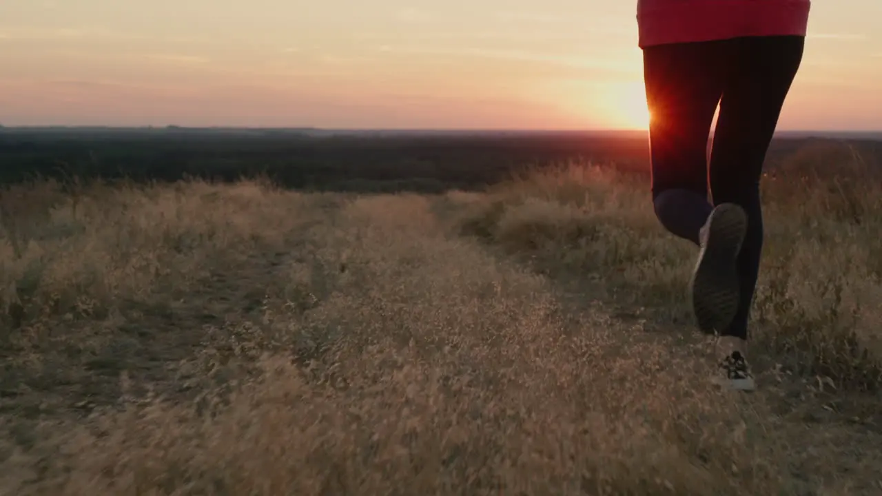 The legs of a woman running at sunset