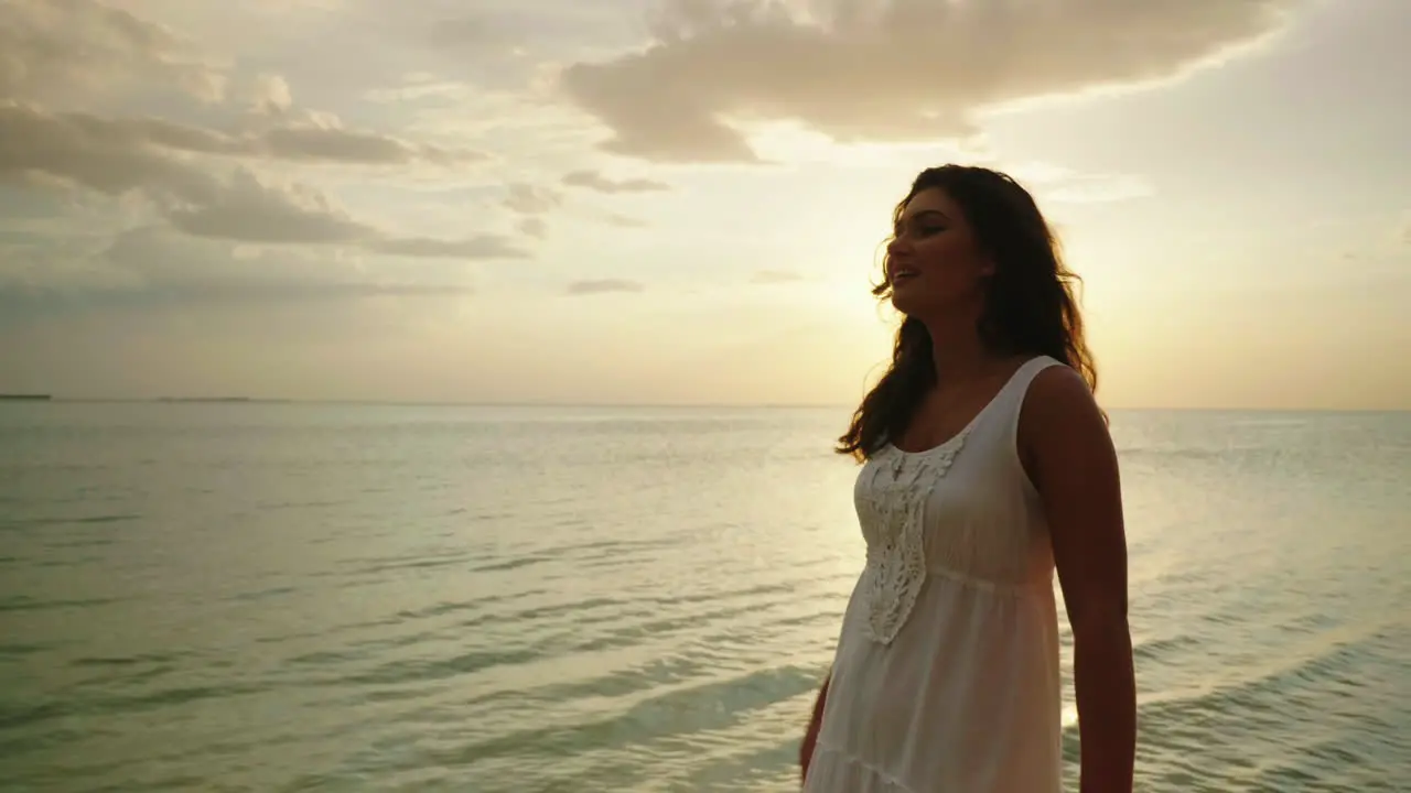 A Young Woman In A Light Summer Dress Is Walking Along The Edge Of The Water Against The Background 