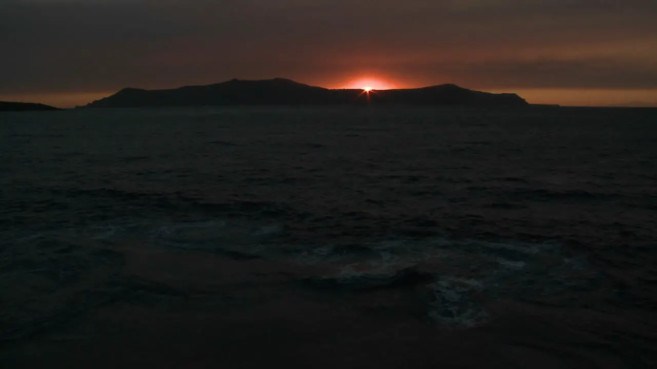 The sun sets behind an island in the ocean 1