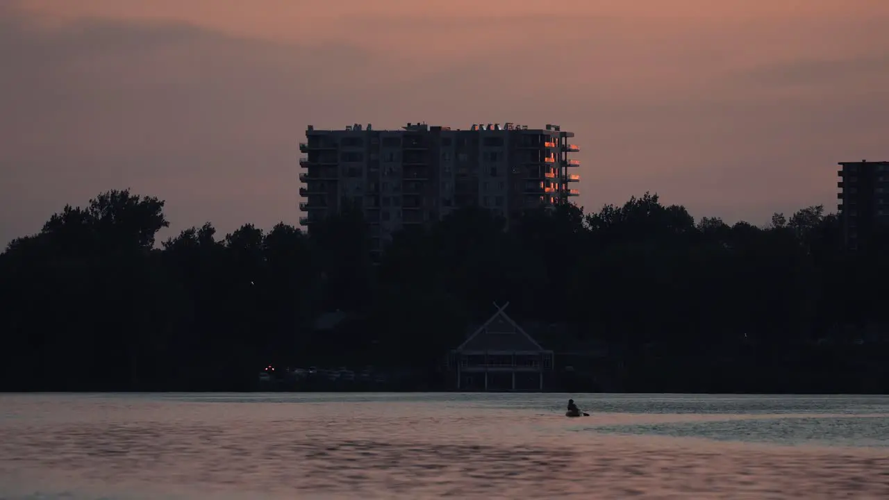 Glorious Sunset Scenery At The Lake Of Nations In Sherbrooke Quebec Canada With A Person Paddling In A Boat And Modern Building In The Background wide shot