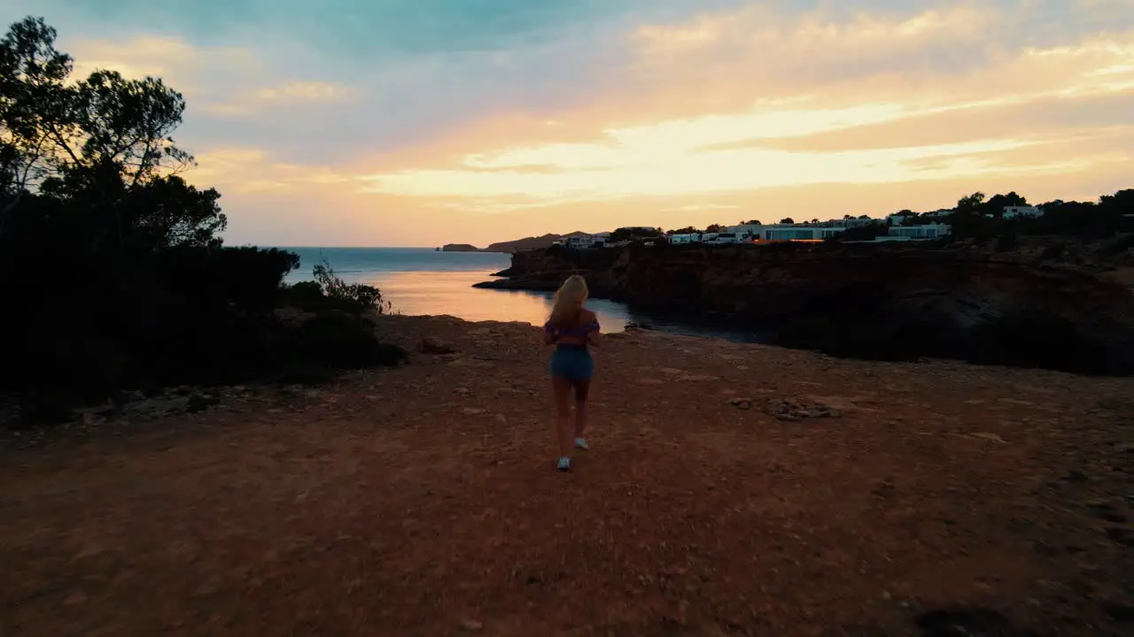 Female Jogging To Edge Of Cliff To Witness Golden Hour Sunset