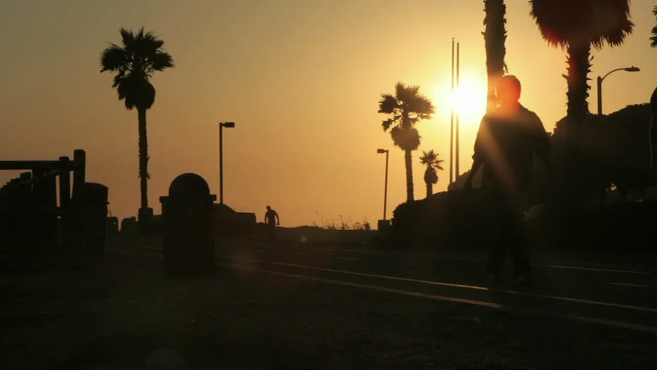 Pedestrians move to and fro on a silhouetted beach front in time lapse