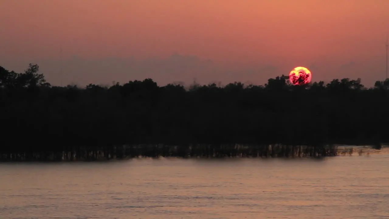 Wide shot sun setting over a river from the POV from a cruise ship