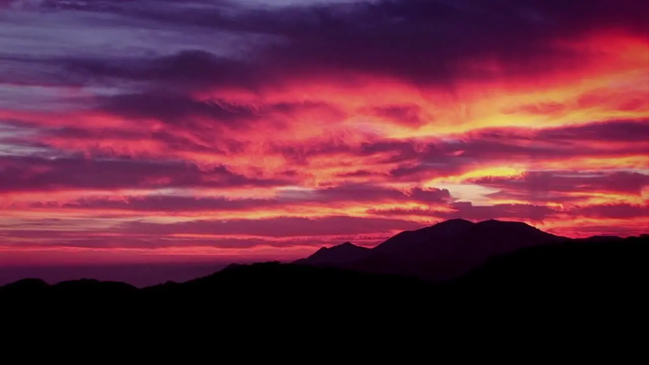 A man climbs a mountain as the sun sets