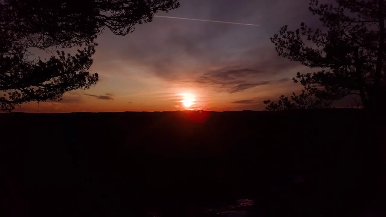 Aerial drone shot flying between trees towards the sunset at the Dyblemyrheia hill on sunny autumn day in Lillesand Aust-Agder South Norway