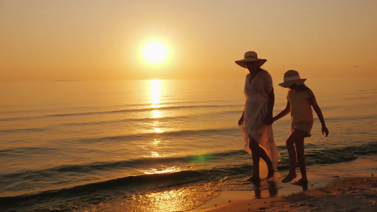 Summer Vacation With A Child A Woman With Her Daughter Strolling Along The Seashore At Sunset Stea