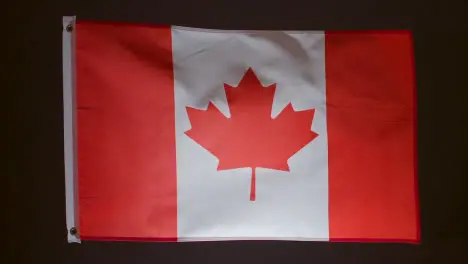 Studio Shot Of Flag Of Canada Flying Against Black Background