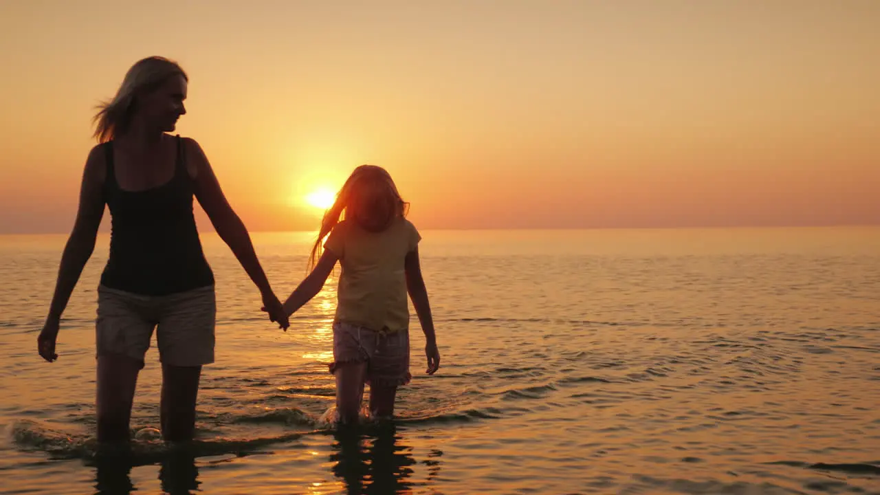 A Young Mother With A Child Is Walking On The Water In Shallow Water 4K Video