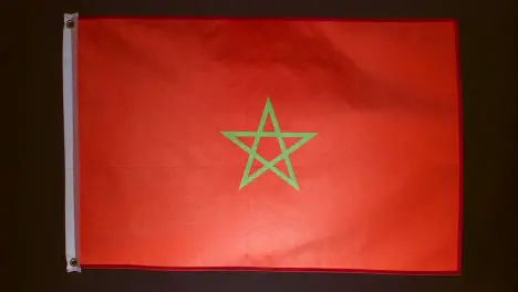 Studio Shot Of Flag Of Morocco Flying Against Black Background