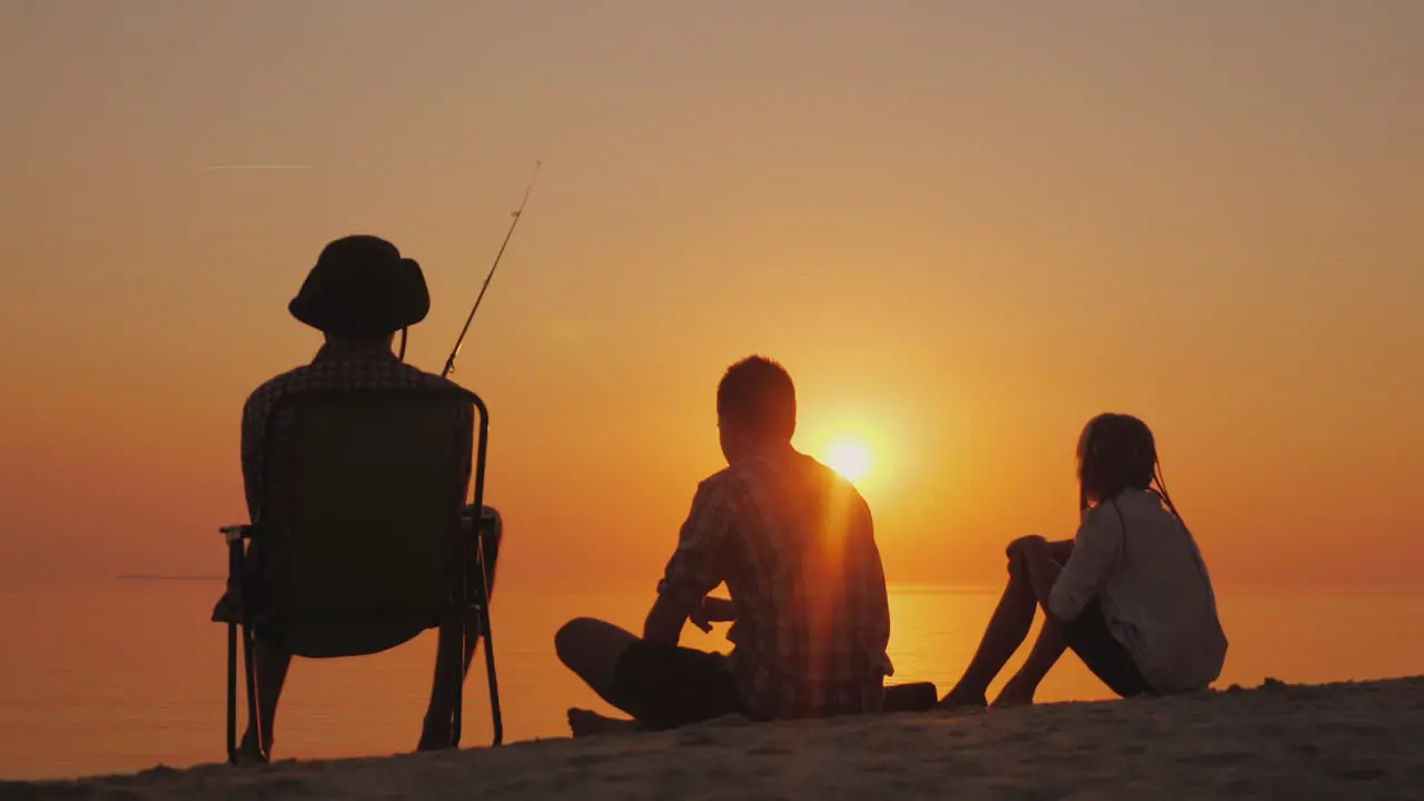 Three Teenagers Are Fishing On The Shore Of The Lake At Sunset Happy Childhood Concept 4K Video