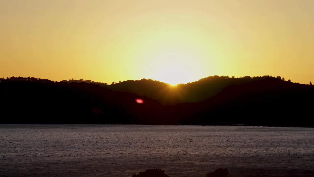 Aerial timelapse shot passing over a lonely river in middle of mountains at sunset