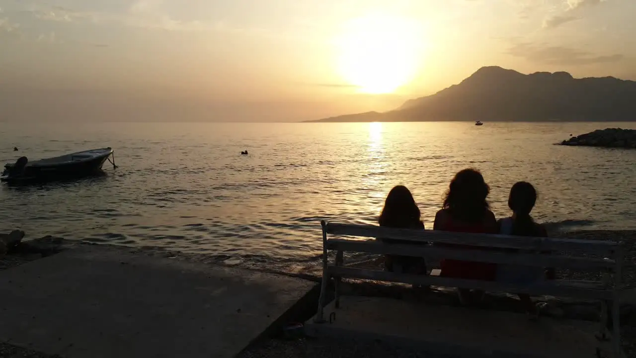 Silhouette of people sitting on a bench against the sunset over the Jadran Sea